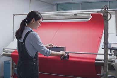 Female worker inspecting bulk fabric rolls for production consistency