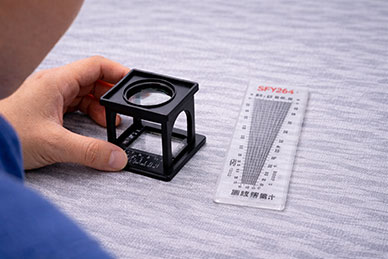 Inspector using magnifying glass to check yarn density and GSM tolerance